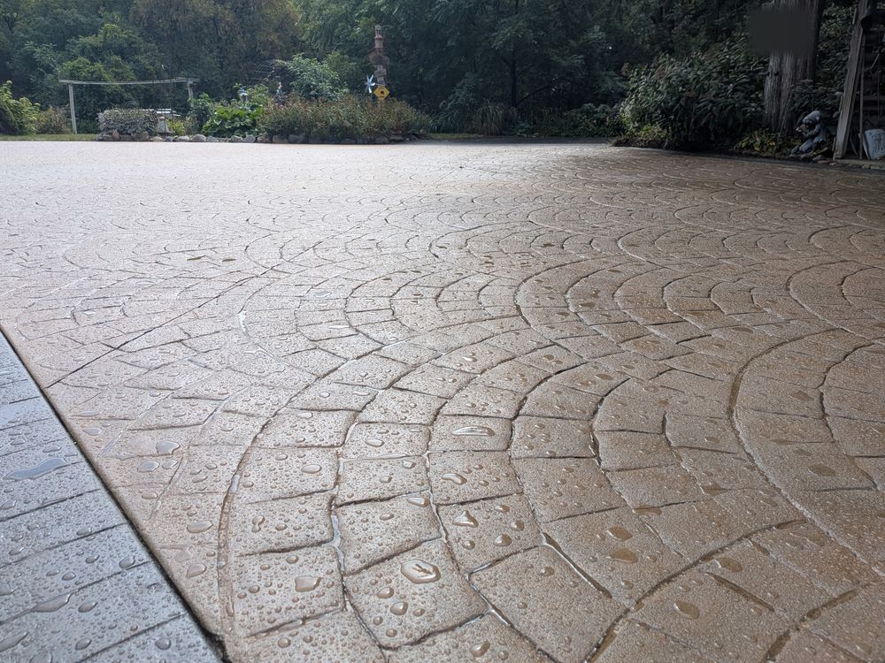 Close-up of the resealed stamped-concrete surface on the same driveway, with water beading on the fan pattern